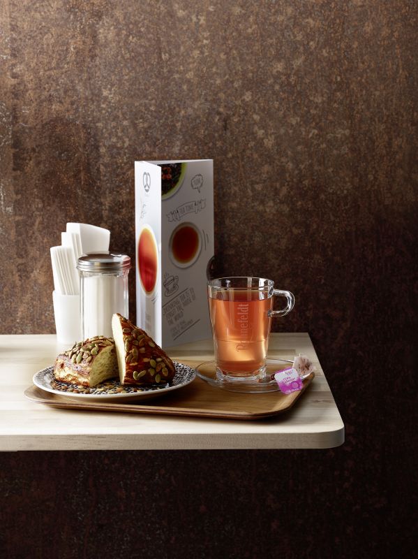 Gedeck mit Tee, Brötchen, Getränkekarte, Zuckerglas und Servietten